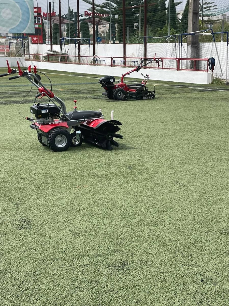 Máquinas de escovagem da Primegramas sobre a relva sintética de um campo de futebol