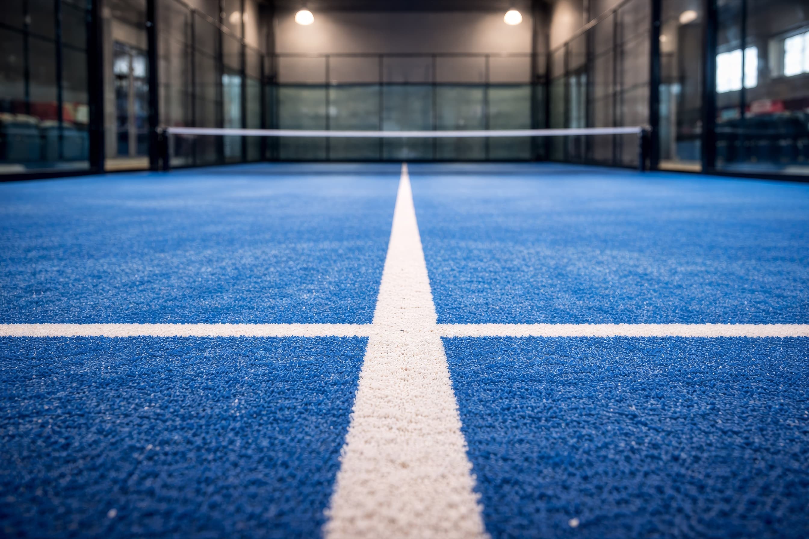Campo de padel indoor com tela de proteção e iluminação