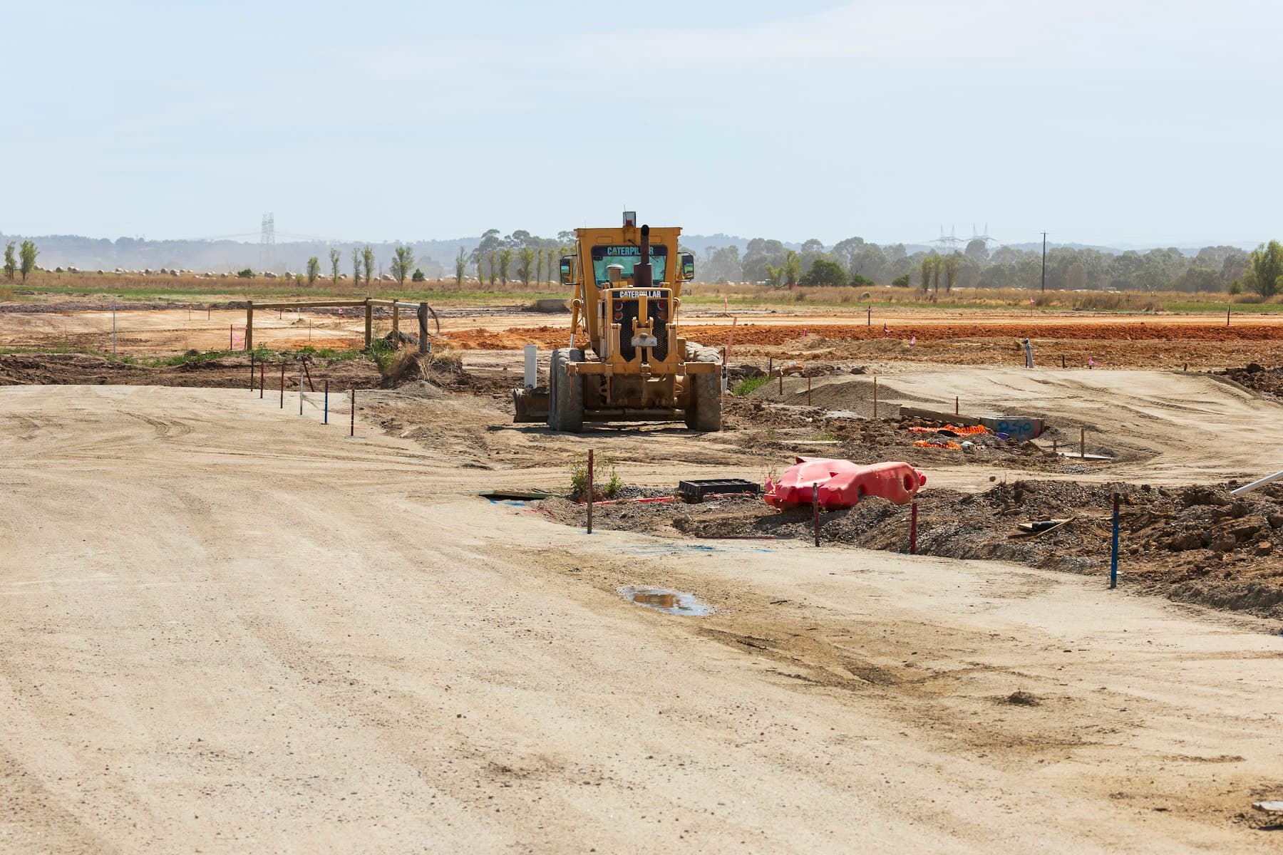 Terreno em obra, com máquinas a preparar e a compactar a base